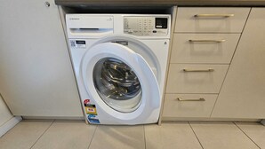 Een voorlader wasmachine met bedieningspaneel, een QR-code en een energielabel.