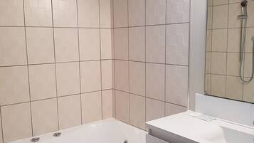 A modern bathroom with a bathtub, a sink, and a shower.