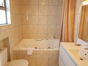 A bathroom with a bathtub, toilet, and sink. - De Lago Motel Apartments (Christchurch)