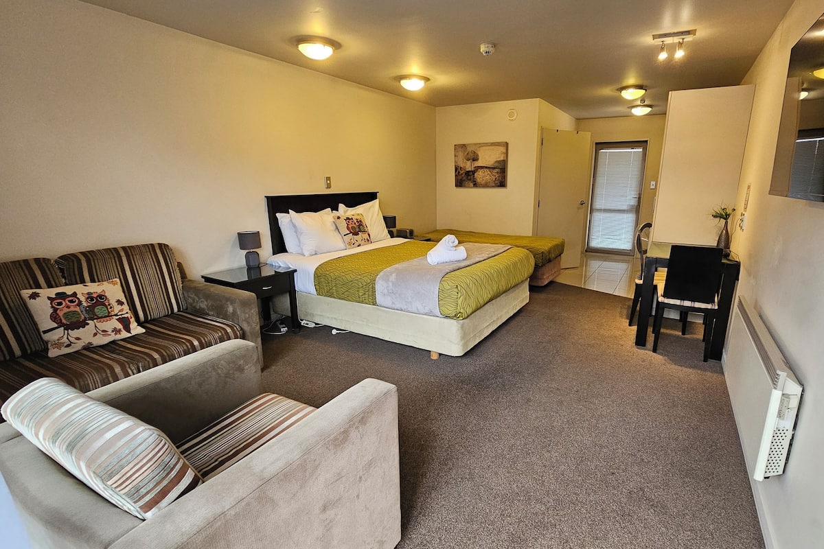 Une chambre d’hôtel avec un lit, un canapé, un bureau et une chaise.