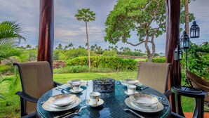 A table set for four with a view of a lush garden and palm trees. - Fairways at Mauna Lani (Kamuela)