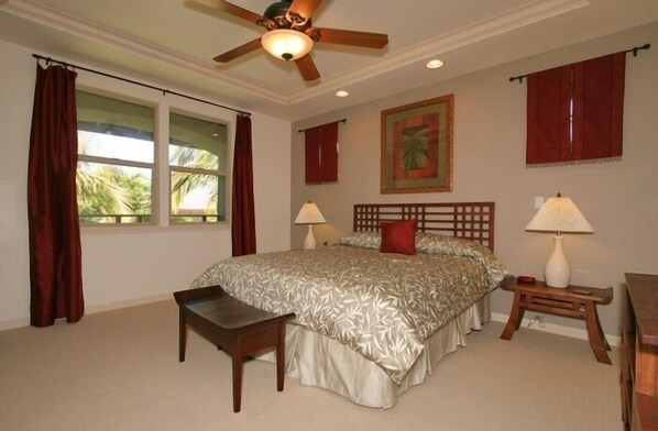 A bedroom with a bed, a desk, a chair, a ceiling fan, and a window with curtains. - Fairways at Mauna Lani (Kamuela)