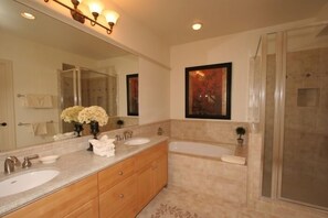 A bathroom with two sinks, a large mirror, and a shower area.