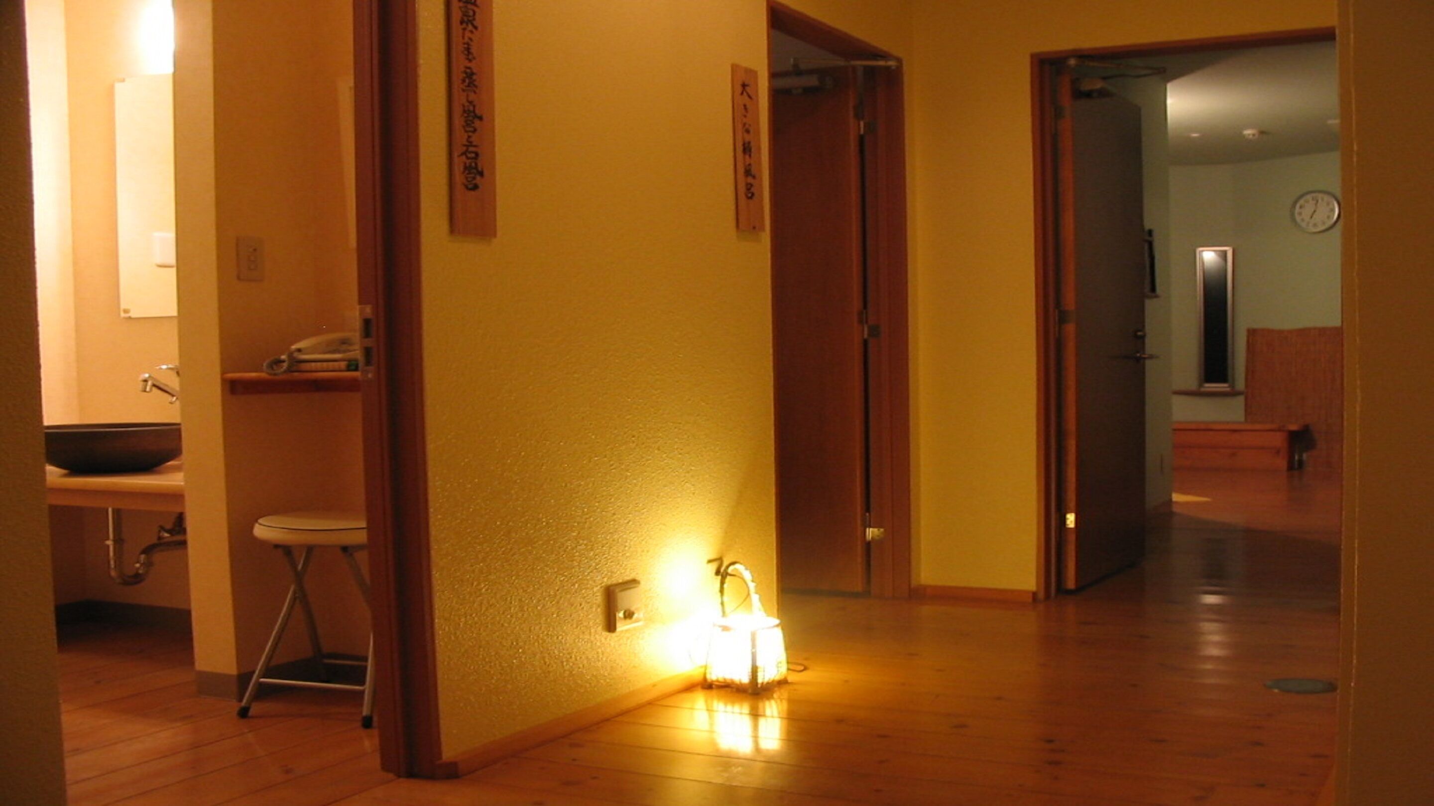 Un couloir avec un plancher en bois, un lavabo et une chaise dans une pièce.