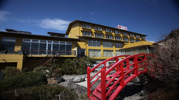 Un edificio amarillo con varias ventanas y una estructura de puente rojo en primer plano.