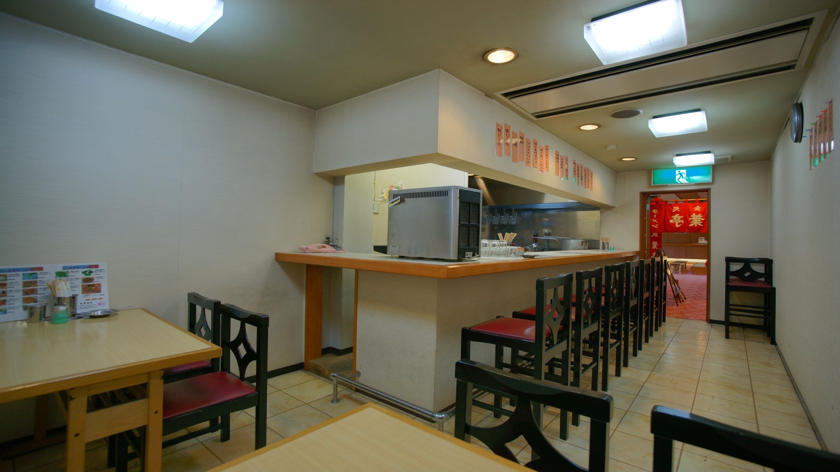 A restaurant interior with a counter, chairs, and a menu board.