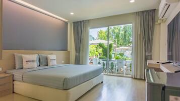 Habitación de hotel con cama, mesitas de noche, escritorio con computadora y vista al exterior.