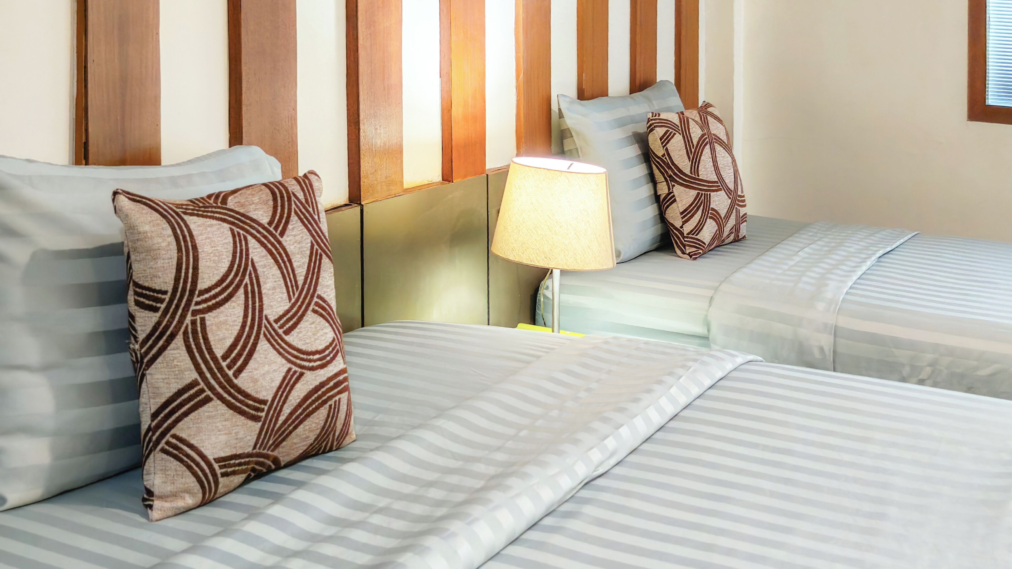 Una habitación de hotel con dos camas, ropa de cama a rayas y almohadas estampadas.