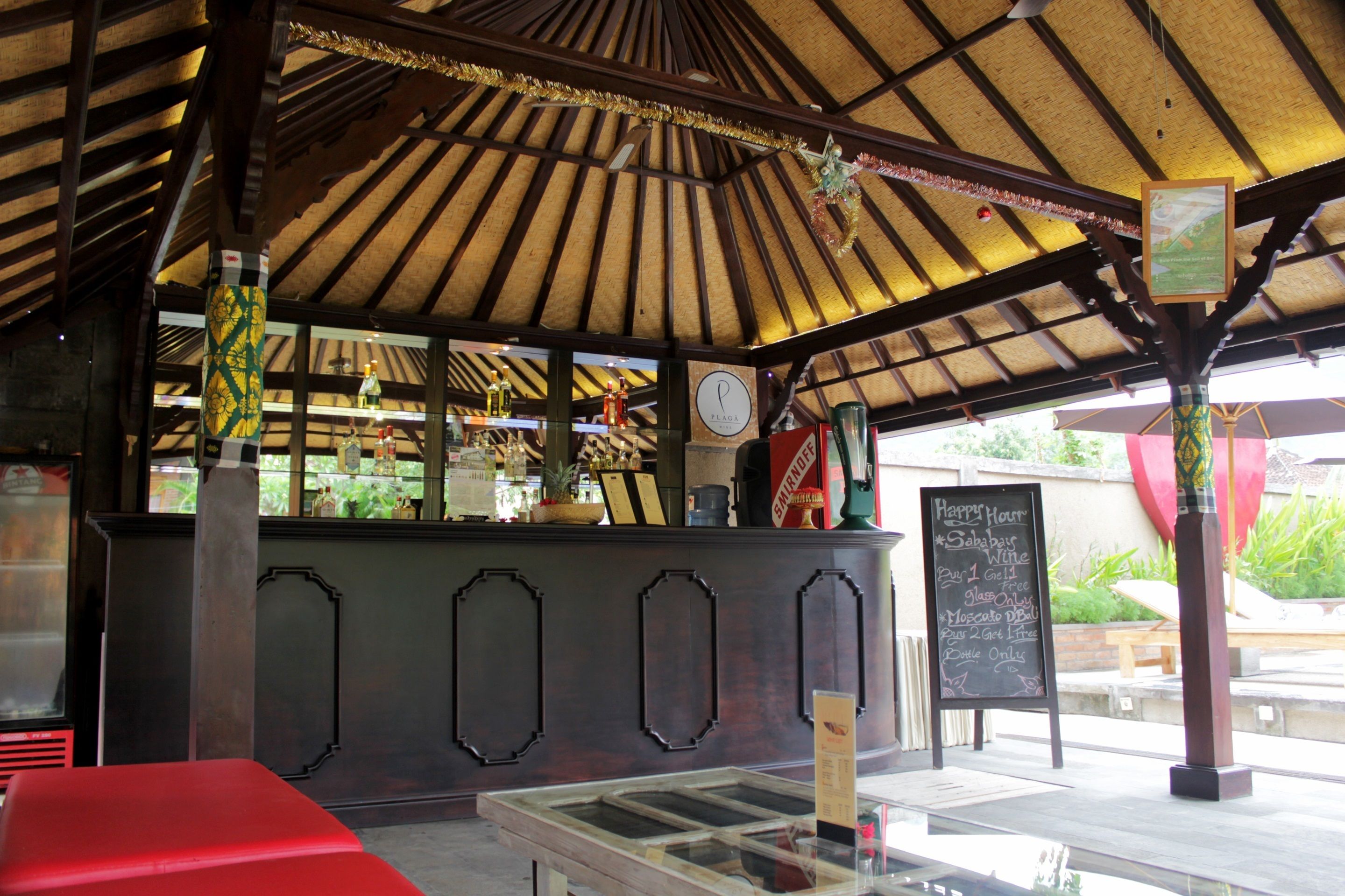 A restaurant with a wooden ceiling, a counter with various bottles, and a chalkboard menu.