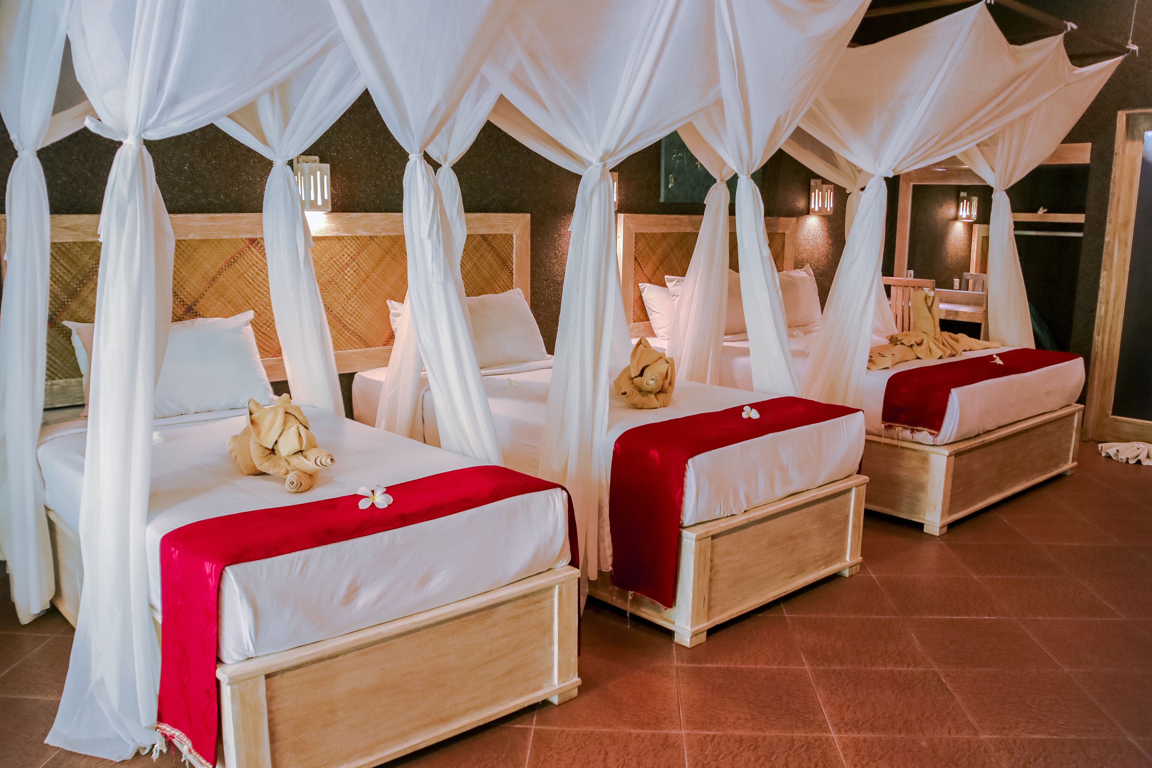 A room with four beds, each with a canopy and white bedding.