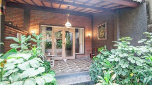 A brick building with a wooden porch, a glass door, and a Buddha statue on the wall.