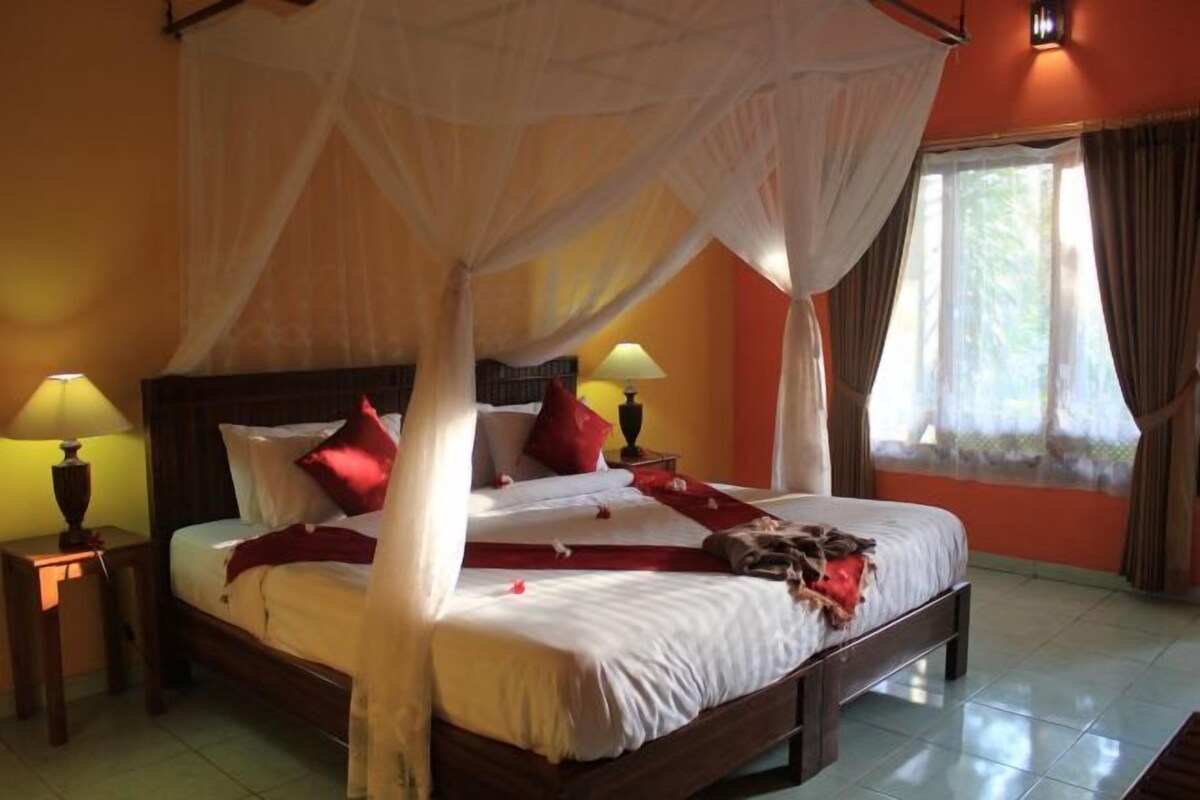 A four-poster bed with a canopy, two bedside lamps, and a window with curtains.