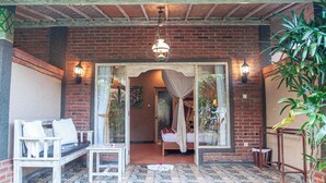 A room with a bed, a bench, and a table. There are two wall-mounted lights and a hanging light fixture.