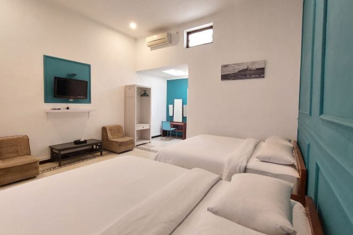 Habitación de hotel con dos camas, televisión, escritorio y una silla.