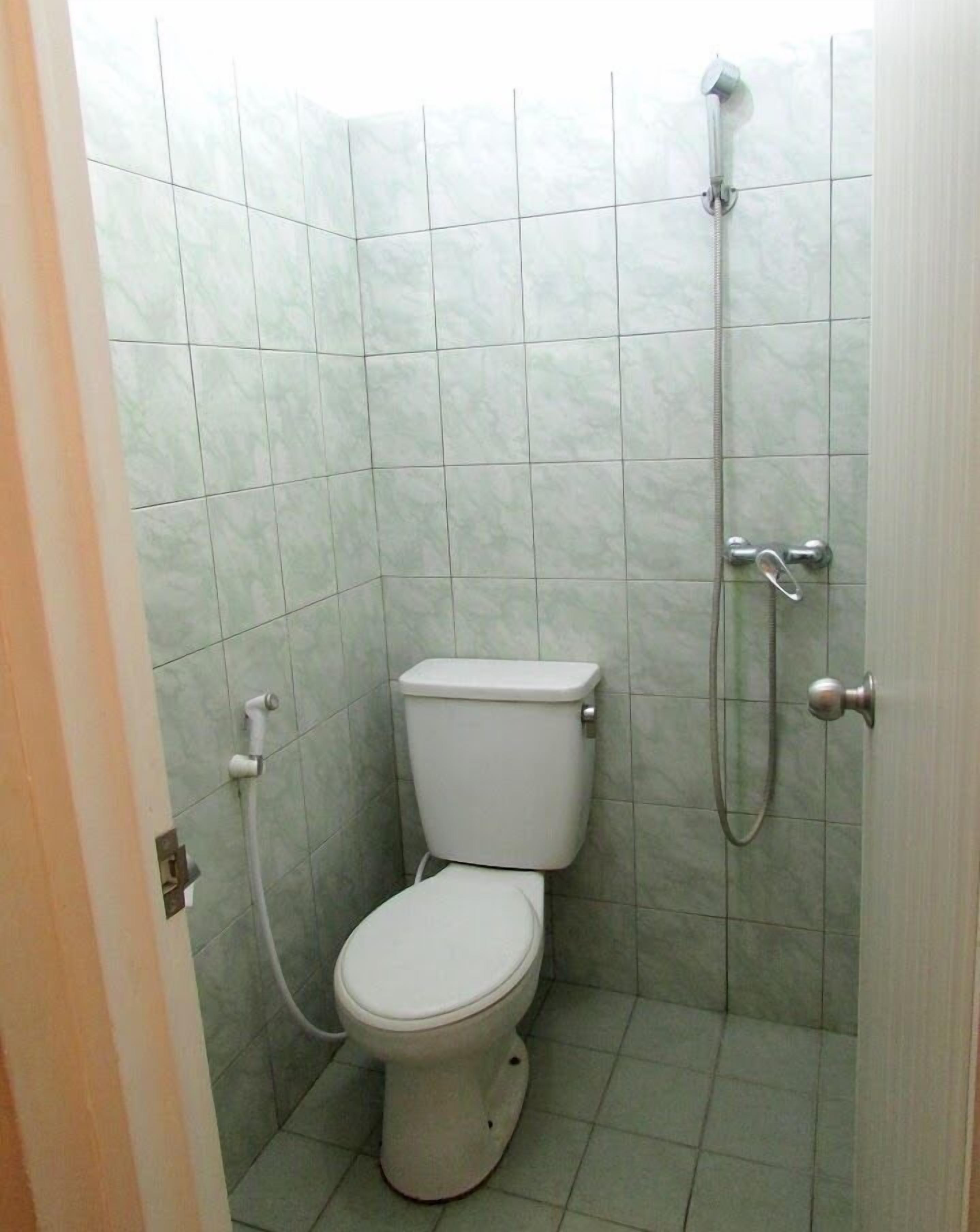 A small, tiled bathroom with a toilet and a shower.