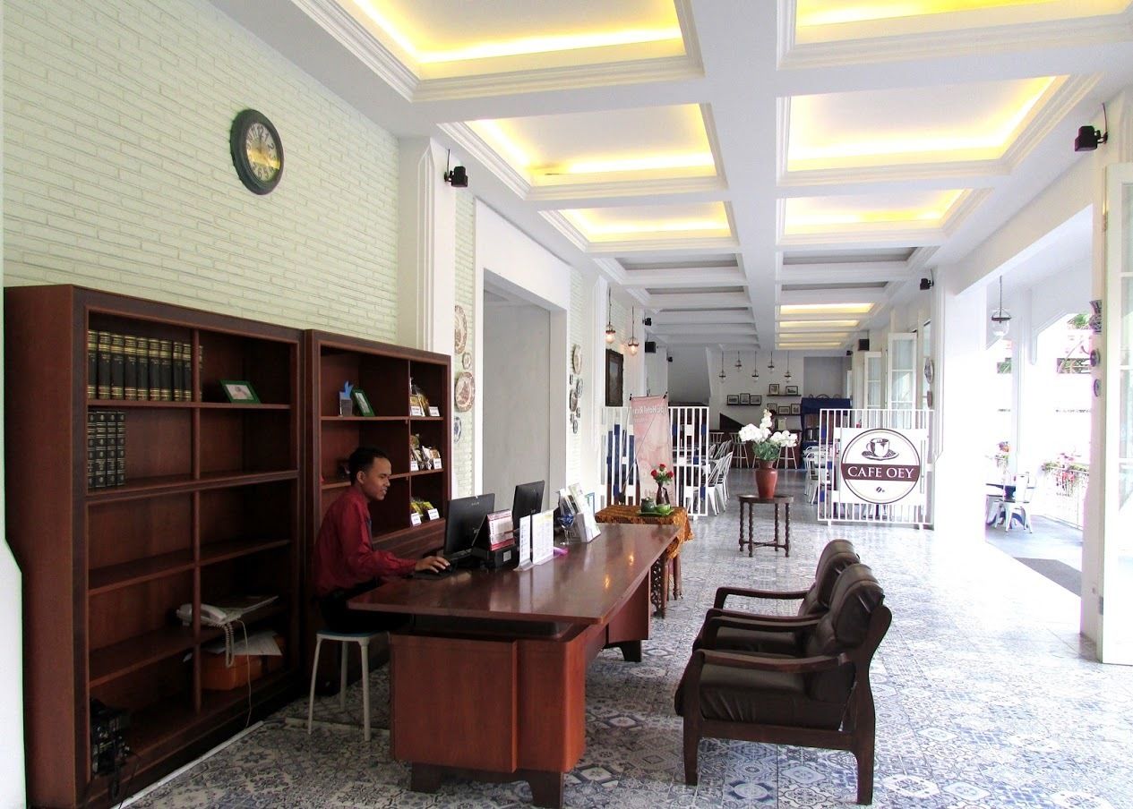 A spacious office with a long desk, a bookshelf, and a computer. There is a clock on the wall and a sign that reads "CAFE OEY."