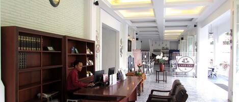 A spacious office with a long desk, a bookshelf, and a computer. There is a clock on the wall and a sign that reads "CAFE OEY."