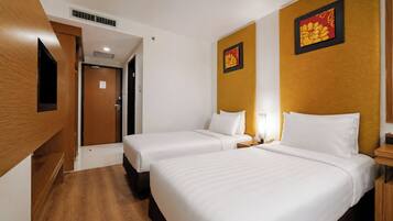 A hotel room with two beds, a wooden wardrobe, and two wall-mounted artwork pieces.