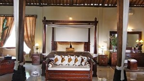 A spacious bedroom with a large bed, ornate wooden ceiling, and a detailed rug. - Joglo Plawang Boutique Villa (Pakem)