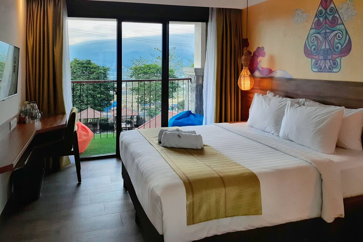 A hotel room with a large bed, a desk, and a view of the outdoors.