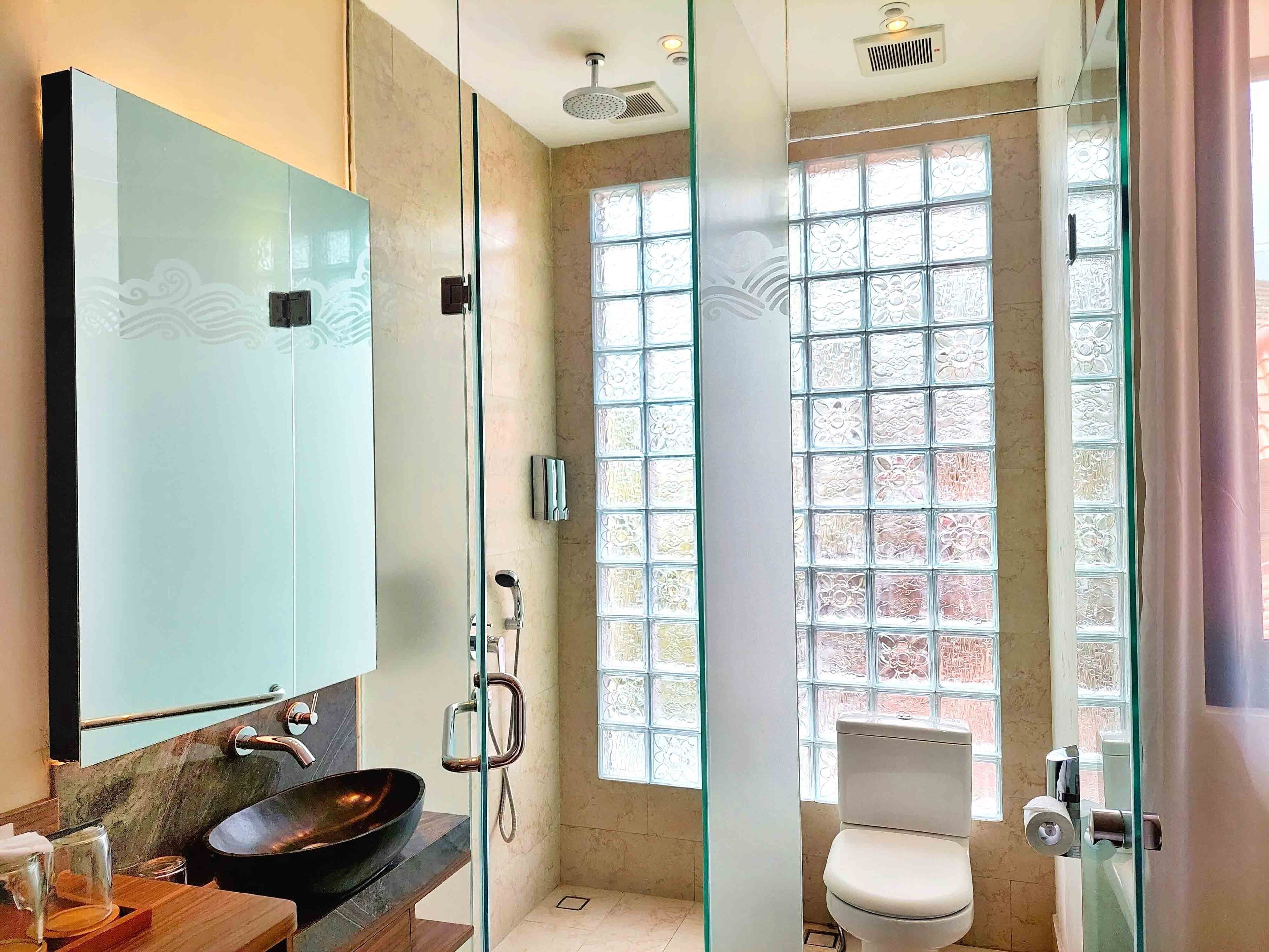 Ein modernes Badezimmer mit einer begehbaren Glasdusche, einem großen Spiegel und einer Toilette.