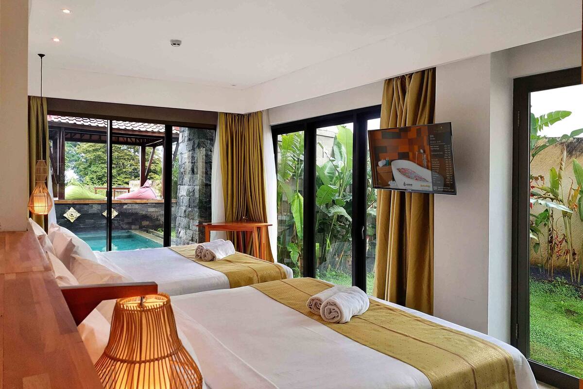 Une chambre d’hôtel avec deux lits, une télévision, une vue sur la piscine et une grande fenêtre avec des rideaux.