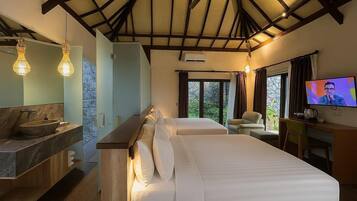 Habitación de hotel con cama, escritorio con televisor, baño con lavamanos y un amplio ventanal con cortinas.