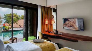 A hotel room with two beds, a TV displaying a reflexology service, a window with a view of a swimming pool and outdoor area, and a small table with a lamp and a bottle.