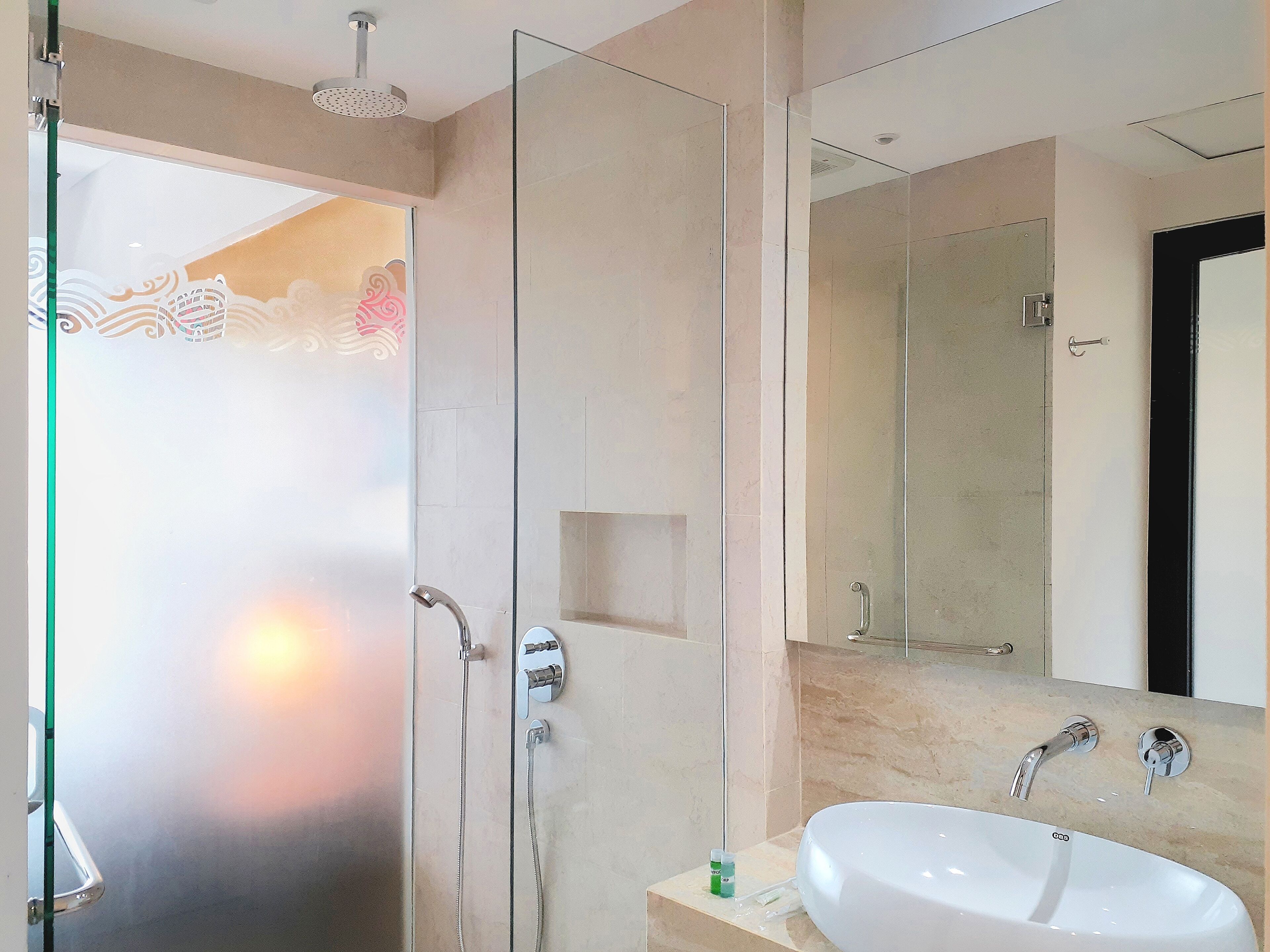 Un baño moderno con cabina de ducha de vidrio, un lavabo blanco y un espejo grande.