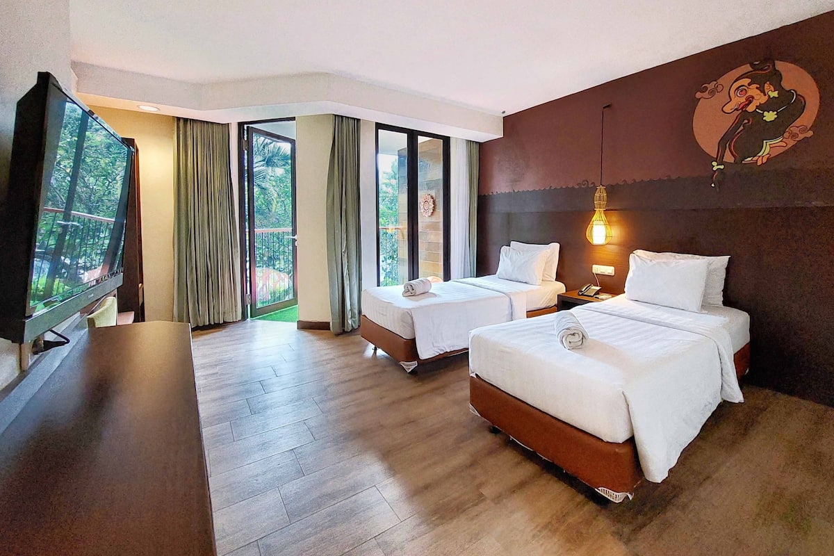 Une chambre d’hôtel avec deux lits, une télévision et un balcon avec des rideaux.