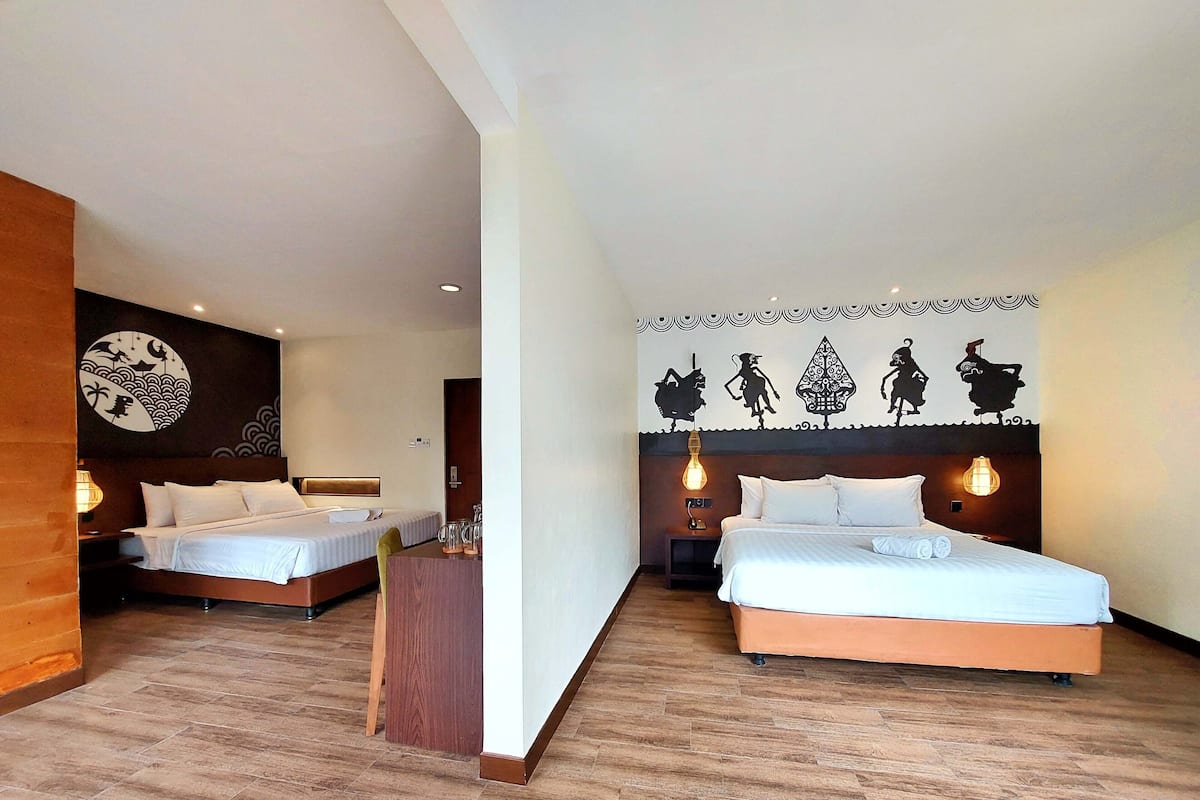 Une chambre d’hôtel avec deux lits, un plancher en bois et un mur orné de motifs décoratifs.