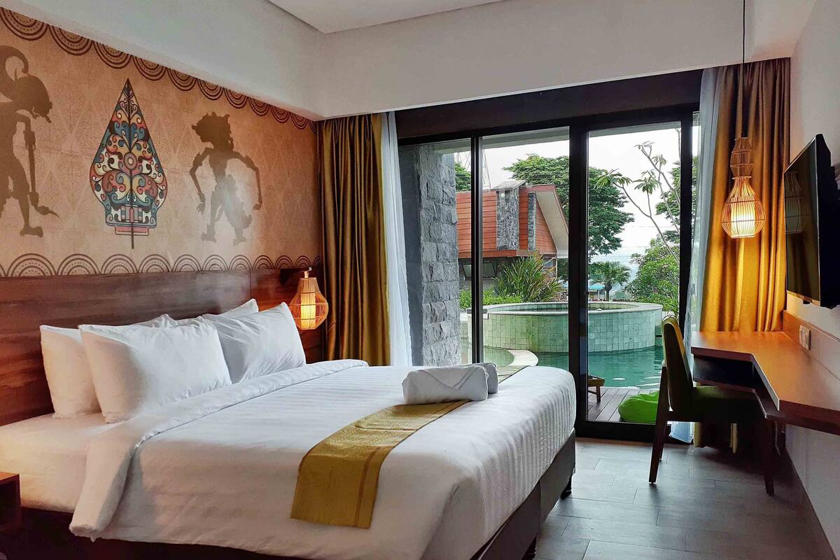 Une chambre d’hôtel avec un grand lit, un bureau et une vue sur une piscine.