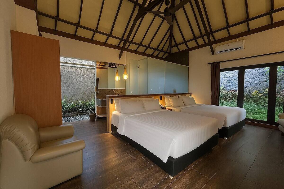 Une chambre avec deux lits, un plafond en bois et une vue sur la verdure.