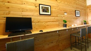 Un mur en bois orné de tableaux encadrés, un ordinateur et deux chaises.