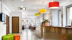 A modern hotel lobby with a reception desk, seating area, and a corridor leading to rooms. - Sure Hotel by Best Western Nologo (Genoa)