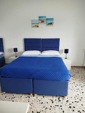 Een slaapkamer met een groot bed, twee nachtkastjes en een muur met drie ingekaderde foto's.
