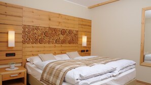 A bedroom with a wooden headboard, a bed with white bedding, two bedside tables, and a mirror on the wall. - Residence Marisol (Mezzana)