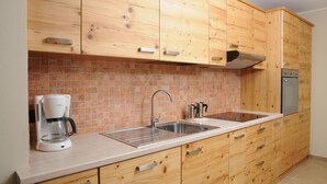 A kitchen with wooden cabinets, a stainless steel sink, a coffee maker, and a stove. - Residence Marisol (Mezzana)