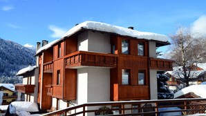A wooden chalet with a balcony, surrounded by snow-covered mountains. - Residence Marisol (Mezzana)