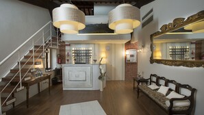 Un amplio salón con escalera, una isla central con lámpara, sofá y un espejo grande en la pared.