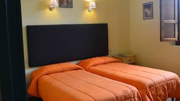Una habitación de hotel con dos camas, una mesita de noche y dos lámparas de pared.