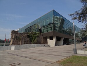 A modern building with a glass facade, a stone archway, and a paved plaza with bicycles. - Hotel Restaurant Bockshaut (Darmstadt)
