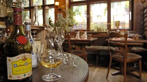 A restaurant interior with wooden tables, chairs, and a variety of wine bottles and glasses on a table. - Hotel Restaurant Bockshaut (Darmstadt)