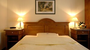 A hotel room with a wooden headboard, two bedside tables with lamps, a framed picture on the wall, and a bed with white bedding. - Hotel Restaurant Bockshaut (Darmstadt)