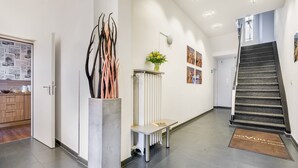 Een moderne hotellobby met een trap, een receptiebalie en een prikbord.