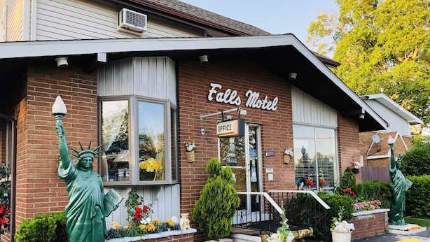 Un motel à la façade en briques, une enseigne indiquant « Falls Motel », et deux statues de la Statue de la Liberté.