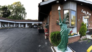 Un motel avec une statue de la Statue de la Liberté, une façade en briques et un parking.