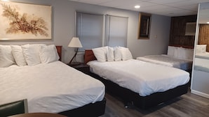Une chambre d’hôtel avec deux lits, un bureau, une lampe et un grand tableau abstrait.