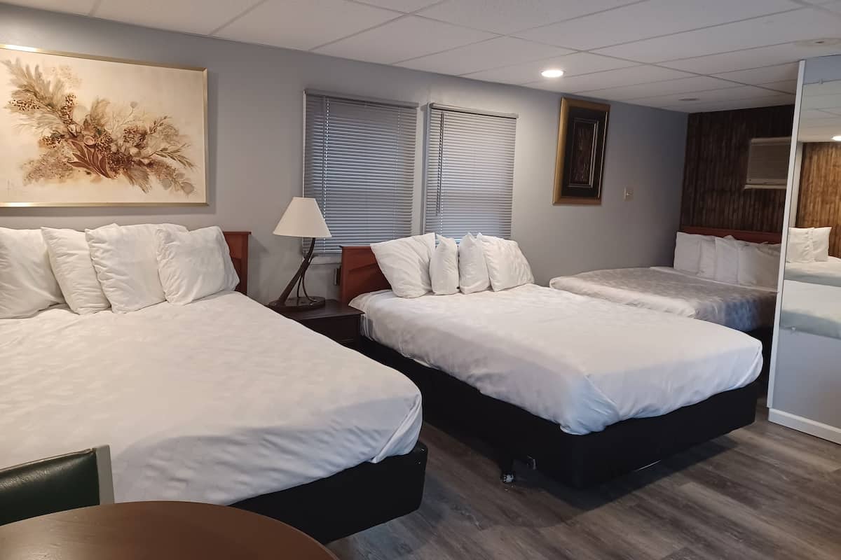 Une chambre d’hôtel avec deux lits, un bureau, une lampe et un grand tableau abstrait.