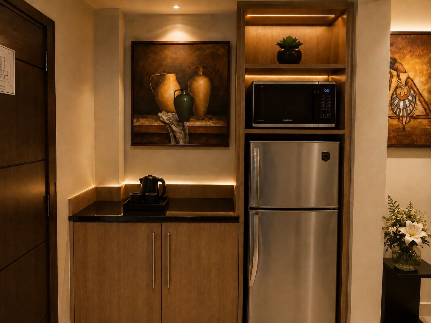 A kitchen with a stainless steel refrigerator, a microwave, and a painting above the counter.
